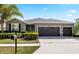 Charming single-story home with a three-car garage, mature landscaping, and a well-manicured lawn at 5453 Suncatcher Dr, Wesley Chapel, FL 33545