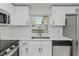 Close up of the kitchen sink featuring stainless steel appliances and bright white cabinets at 6136 56Th N Ave, St Petersburg, FL 33709