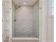 Elegant shower with textured tile, pebble floor, and modern gold shower head at 6136 56Th N Ave, St Petersburg, FL 33709