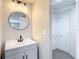 Bathroom with modern vanity, round mirror, and an adjacent walk-in closet for storage at 9201 Spy Glass Ct, Tampa, FL 33615