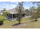 A lush backyard with a sunroom addition featuring white rock landscaping and mature trees at 9723 Rolling Cir, San Antonio, FL 33576