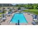 Aerial view of a community pool with tables, chairs, shade umbrellas, and a bocce ball court at 9723 Rolling Cir, San Antonio, FL 33576