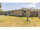 The back of the home with a screened patio and fenced yard with lush green grass at 10016 Glen Moor Ln, Port Richey, FL 34668