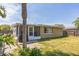 The back exterior of the home showing a screened patio, privacy fence, and lawn at 10016 Glen Moor Ln, Port Richey, FL 34668