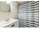 Clean bathroom with a single sink vanity, mirror, and striped shower curtain at 10016 Glen Moor Ln, Port Richey, FL 34668