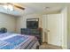 Well-lit bedroom with dresser, television, and door to the en-suite bathroom at 10016 Glen Moor Ln, Port Richey, FL 34668