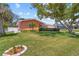 Beautiful house with a green lawn, manicured shrubbery and a mature tree provides ample shade at 10448 Hetrick W Cir, Largo, FL 33774