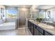 Bathroom with a granite double sink vanity, garden tub and glass door shower at 10645 Bridgegate Heights Loop, San Antonio, FL 33576