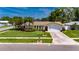 Exterior view of a well-maintained home with a green lawn, garden, and a driveway leading to the garage at 12933 90Th Ave, Seminole, FL 33776