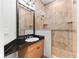Bathroom with granite counters, vanity cabinet, walk-in shower, and decorative tile work at 1600 Magnolia Rd, Belleair, FL 33756