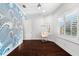 Bright bedroom with a decorative wave-patterned wall, hanging hammock chair, and hardwood floors at 1600 Magnolia Rd, Belleair, FL 33756