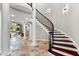 Grand foyer with a winding staircase, travertine flooring, and classic architectural columns at 1600 Magnolia Rd, Belleair, FL 33756
