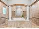 Luxurious bathroom with a centered tub and arched shower framed by columns and patterned tile at 1600 Magnolia Rd, Belleair, FL 33756