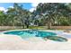 In-ground pool and spa surrounded by trees, shrubs, and a stone paver patio in a backyard setting at 1600 Magnolia Rd, Belleair, FL 33756