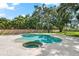 An in-ground pool and spa is surrounded by stone pavers, trees and shrubbery at 1600 Magnolia Rd, Belleair, FL 33756