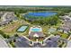 An aerial view highlights a community pool, tennis court, and park with lake in background at 1741 Cherry Walk Rd, Lutz, FL 33558