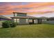 Spacious backyard features a covered patio, lush green lawn, and serene sunset backdrop at 1741 Cherry Walk Rd, Lutz, FL 33558