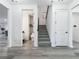 Bright entryway featuring gray wood-look floors and a staircase, with a half-bath visible to the left at 17683 Ramble On Way, Land O Lakes, FL 34638