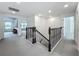 Hallway shows the decorative iron stair railing, plush carpet, and a view to the Gathering room at 17683 Ramble On Way, Land O Lakes, FL 34638