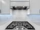 Close-up of a modern range and hood with a subway tile backsplash and quartz countertops at 17683 Ramble On Way, Land O Lakes, FL 34638