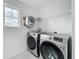 Modern laundry room equipped with front load washer and dryer and a built in wall shelf at 17683 Ramble On Way, Land O Lakes, FL 34638