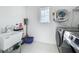Bright laundry room features white walls, modern washer/dryer, utility sink, and natural light from the window at 17683 Ramble On Way, Land O Lakes, FL 34638