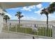 Balcony view with lush green lawn, tropical palms, and sandy beach with blue skies at 17960 Gulf Blvd # 225, Redington Shores, FL 33708