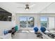Bright fitness room with mirrored wall, TV, and exercise equipment, leading to balcony with water view at 2233 Donato Dr, Belleair Beach, FL 33786