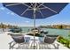 Relaxing patio area featuring lounge chairs and an umbrella overlooking the waterfront and boat dock at 2233 Donato Dr, Belleair Beach, FL 33786