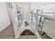Open staircase with glass railings overlooks the living room and pool area, connecting the upper and lower levels at 2233 Donato Dr, Belleair Beach, FL 33786