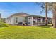 Spacious backyard featuring a screened patio, lush green grass, and mature trees at 23935 Coral Ridge Ln, Land O Lakes, FL 34639