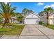 Charming home with a well-manicured lawn, mature palm trees, and a concrete driveway at 23935 Coral Ridge Ln, Land O Lakes, FL 34639