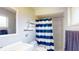 Bright bathroom featuring a shower with striped curtain, floating shelves and large mirror at 3075 Rosery Ne Rd, Largo, FL 33771
