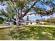 Spacious front yard view of single-story home featuring mature trees and lush green lawn at 3075 Rosery Ne Rd, Largo, FL 33771