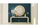 Elegant foyer with a white console table, round mirror, designer lamp, and stylish décor against a blue accent wall at 31744 Parkland Bay Way, San Antonio, FL 33576