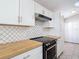 Modern kitchen with white cabinets, butcher block countertops, stainless steel hardware and updated appliances at 36144 Markree Castle Ave, Dade City, FL 33525