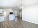 Open-concept living area with kitchen access, features wood-look flooring, and modern chandelier at 36144 Markree Castle Ave, Dade City, FL 33525