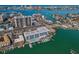 Aerial view of waterfront condos, a pool, and boat docks against the backdrop of a vibrant cityscape at 415 Island Way # 511, Clearwater Beach, FL 33767