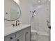 Modern bathroom features a gray vanity, a round mirror, and a glass shower with elegant white tiling at 4224 W Corona St, Tampa, FL 33629