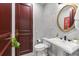 Elegant powder room with marble accent wall, pedestal sink, and gold-trimmed mirror at 429 St Andrews Dr, Belleair, FL 33756