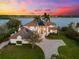 Stunning waterfront estate with lush landscaping, a brick driveway, and gorgeous sunset views at 429 St Andrews Dr, Belleair, FL 33756