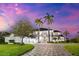 A stately two-story waterfront home features palm trees and a patterned brick driveway at 429 St Andrews Dr, Belleair, FL 33756