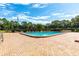 Community pool with ample lounge chairs on a brick patio, surrounded by greenery and sunny skies at 4306 La Mora Ct, Tampa, FL 33611