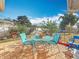 A brick patio area with a teal table and chairs, surrounded by a grassy yard and greenery at 5100 Aragon S Way, St Petersburg, FL 33705
