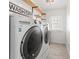 Well-lit laundry room equipped with modern washer and dryer units, complemented by floating wood shelves at 723 S Brevard Ave, Tampa, FL 33606