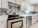 Close-up of a stainless steel stove and gray kitchen cabinets with modern backsplash and quartz counters at 8345 81St Ct, Seminole, FL 33777