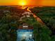 Expansive aerial view of the waterfront property featuring lush landscaping, private boat access, and breathtaking sunset scenery at 8717 Betty St, Port Richey, FL 34668