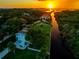 Captivating aerial shot of a waterfront property featuring lush greenery, private boat access, and a breathtaking sunset backdrop at 8717 Betty St, Port Richey, FL 34668