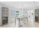 Open-concept dining area with a modern light fixture, glass table, and views of the backyard at 8717 Betty St, Port Richey, FL 34668
