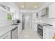 Well-lit kitchen with stainless steel appliances, white cabinets, and access to the laundry area at 8717 Betty St, Port Richey, FL 34668